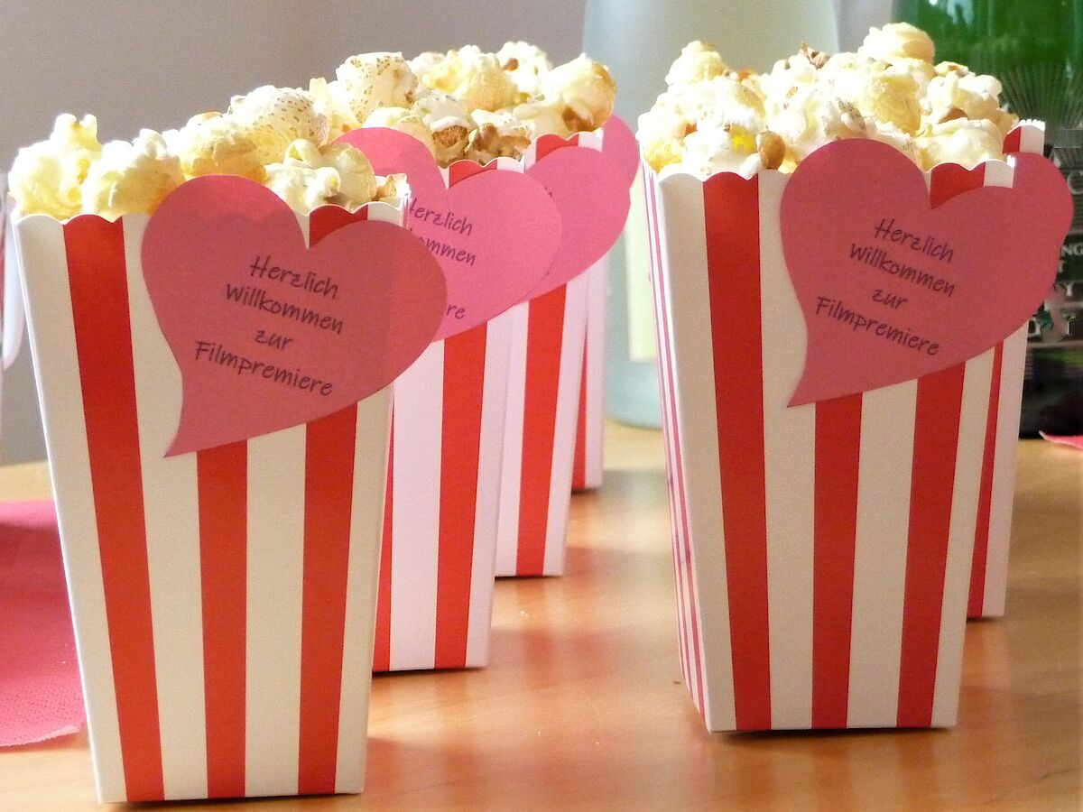 rot-weiß gestreifte Popcorntüten mit Aufschrift: herzlich willkommen zur Filmpremiere